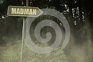 old signboard with text madman near the green sinister forest