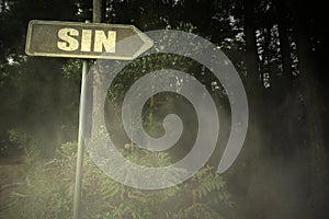 Old signboard with text sin near the sinister forest