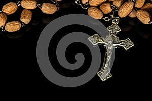 Old silver crucifix with wooden rosary bead on black background