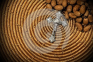 Old silver crucifix and wooden rosary bead on woven wicker texture