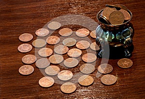 Old Silver Pot and Copper Coins on a Polished Wooden Surface