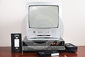 An old silver TV with built-in DVD player and a nearby vintage VCR from the 1980s, 1990s, 2000s. photo
