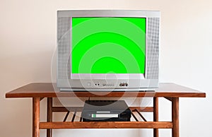 Old silver vintage TV with clutter from 1980s, 1990s, 2000s, VCR on wallpaper background.