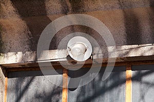 An old a single light bulb and lamp outdoor at front wall door of house, closeup