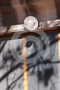 An old a single light bulb and lamp outdoor at front wall door of house, closeup