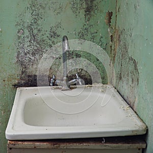 Old sink with a faucet on the background of dirty walls