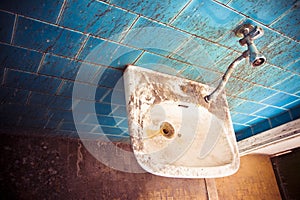 Old sink in a public abandoned restroom - toned image