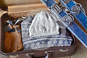 Old ski against  a suitcase with warm clothing