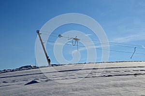 An old ski lift where with the help of a rope and a rod with a plastic plate, which the skier denies, or s sits down and lets hims