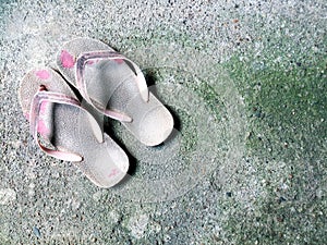 Old slippers on dirty cement background. Pair of shoes  on background.