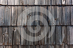 Old slovenian mountain cottage tiled wooden facade, worn wood tiles on exterior wall