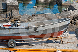 Old small fishing boat on trailer on shore under repair