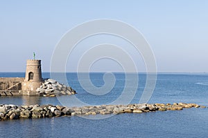 Old small lighthouse and stone wave breakers of Recco on a sunny summer day.