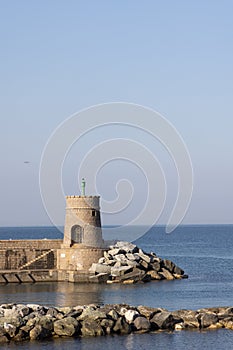 Old small lighthouse and stone wave breakers of Recco on a sunny summer day.