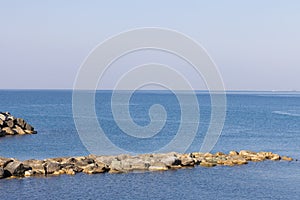 Old small lighthouse and stone wave breakers of Recco on a sunny summer day.