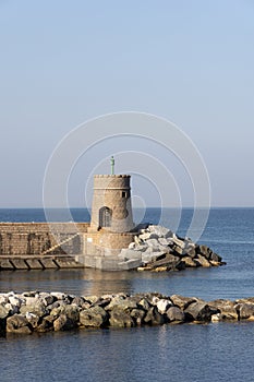 Old small lighthouse and stone wave breakers of Recco on a sunny summer day.