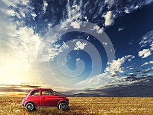 Old small red car Italian vintage. Natural landscape sunset