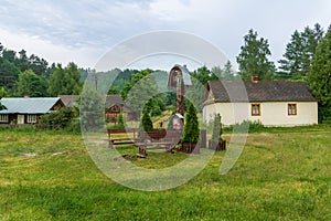 Old, small village houses and agricultural buildings situated in the middle of the forest. Roadside shrine in the foreground