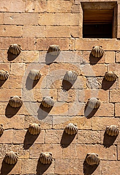 Old small window in a facade of granite blocks and shell moldings on the wall with long shadows from the evening sun in the Casa