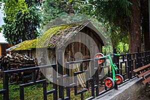 An old small wooden shed and a children`s tricycle on the fence.