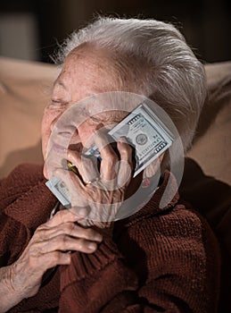 Old smiling gray-haired woman holding dollar cash money