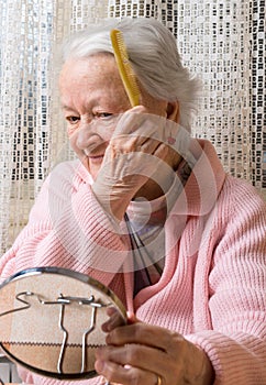 Old smiling woman combing her hair