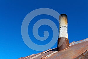 Old smoke pipe out of the rusty iron roof.