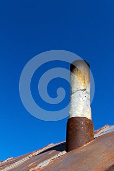 Old smoke pipe out of the rusty iron roof.