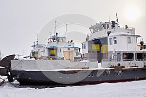 Old snow-covered ferries on the ice-covered river