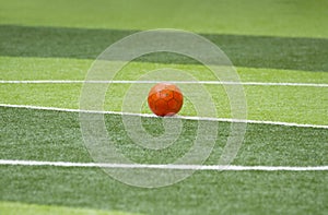 Old soccer ball on artificial green grass field