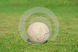 Old soccer ball on green grass of soccer field