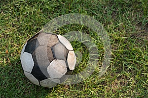 old soccer ball placed on  green grass by top view
