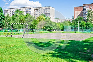 Old soccer field and rusty white soccer goals it the city near the school. Old soccer field overgrown with grass. Old concrete