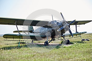 An old Soviet AN 2 aircraft stands in a field on a green meadow