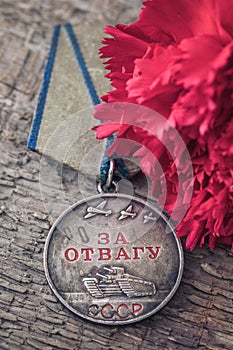 The Old Soviet Medal For Bravery of the Second World War with a red carnation, Victory Day May 9 postcard concept