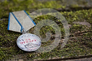 The Old Soviet Medal with written in Russian For Bravery, Second World War, natural moss background, Victory Day May 9