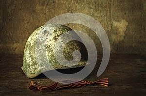 Old Soviet military helmet on a wooden table, St. George`s ribbon