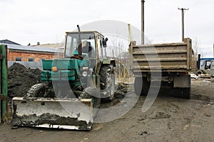 An old Soviet tractor digs and loads waste stone processing