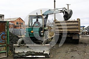An old Soviet tractor digs and loads waste stone processing