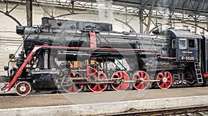 Old Soviet vintage black retro train with a red star at the railway station in Lviv produces steam from the pipes and the passeng