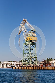 Old Soviet yellow port crane on blue sky background