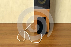 Old speaker linked by usb-cable to smartphone. Clouse-up