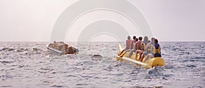 A speedboat rides a family on a yellow banana boat