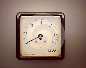 Old square industrial wattmeter with the scale measured in milliwatts with an analogue dial and scale on a grey background