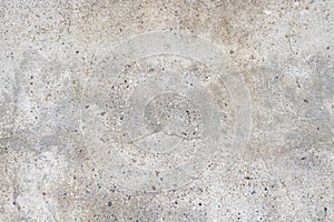 Old stained concrete wall with multi-colored pebble stones. Texture of gray color cement background, dry scratched surface wall