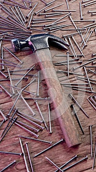 Old stained iron hammer on wooden table surrounded with nails. 3D illustration