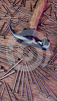 Old stained iron hammer on wooden table surrounded with nails. 3D illustration