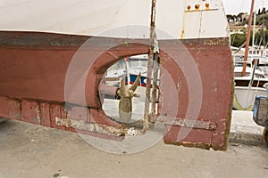 The old stainless steel propeller blades with rust on astern of white and red boat at the dock for fixing, many yacht parking at