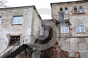 Old staircase and house. An old industrial building with a rusty metal staircase. Collapsed stone structure