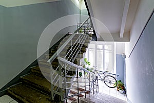 old staircase in the stairwell with wooden railing and wrought-iron lattice